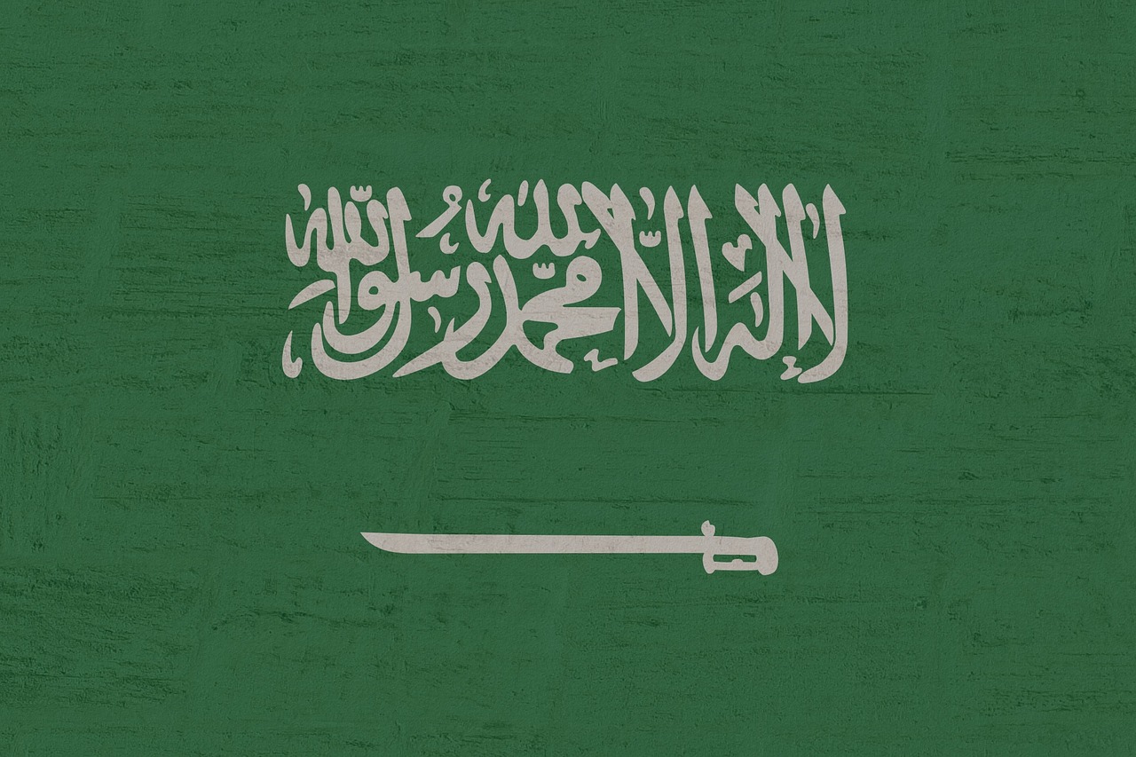 Saudi tourist e-visa approval screen on a laptop with passport and Saudi flag in background