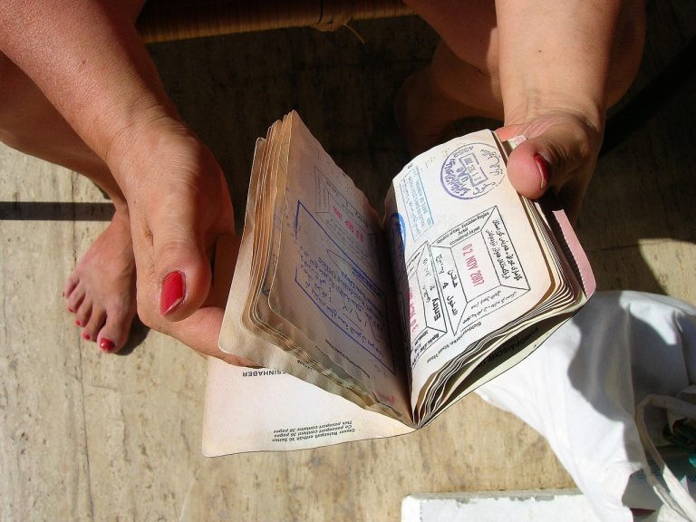 Stack of travel documents including passport, visa page, vaccination certificate on a desk