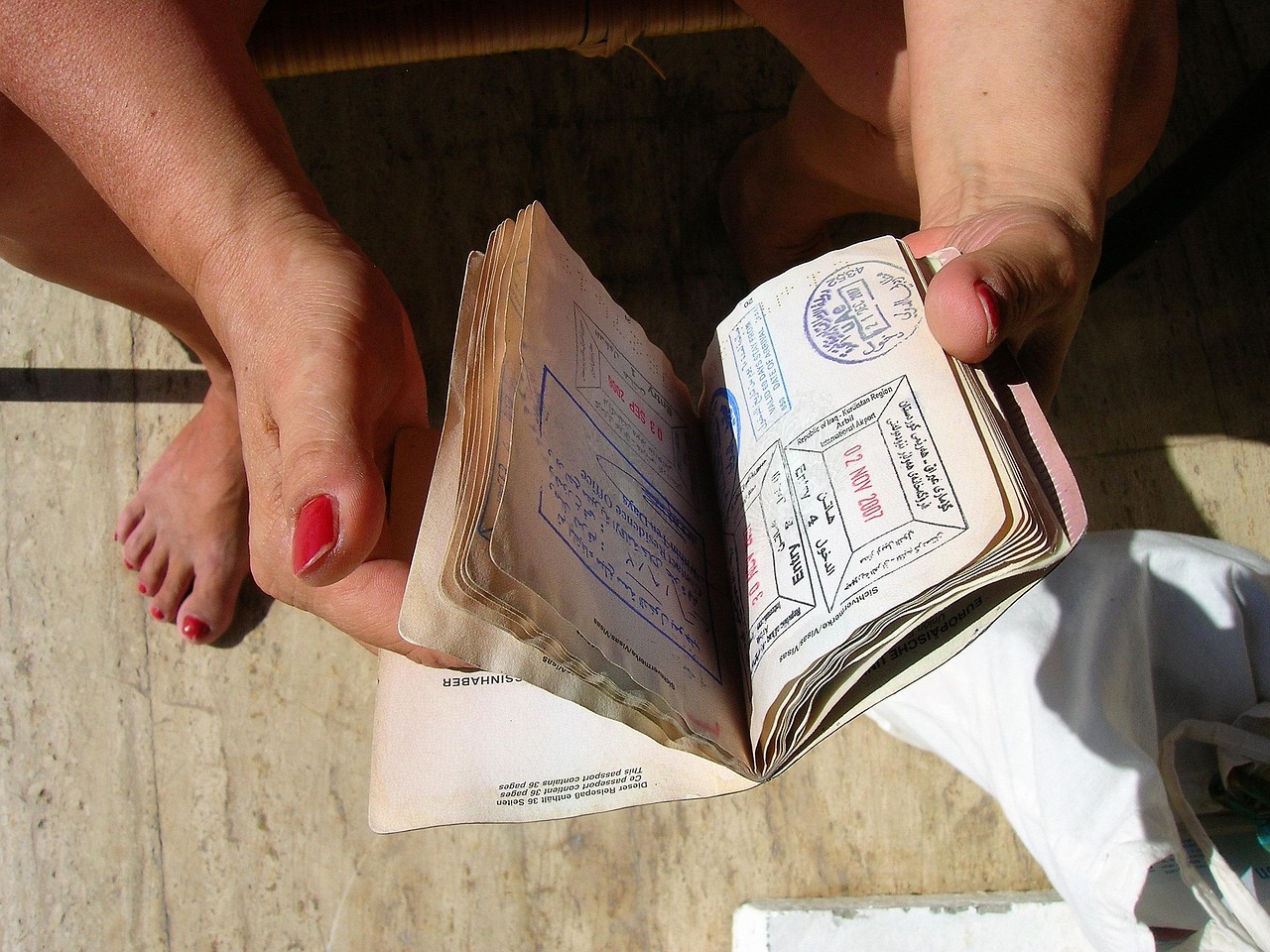 stack of travel documents including passport, visa page, vaccination certificate on a desk