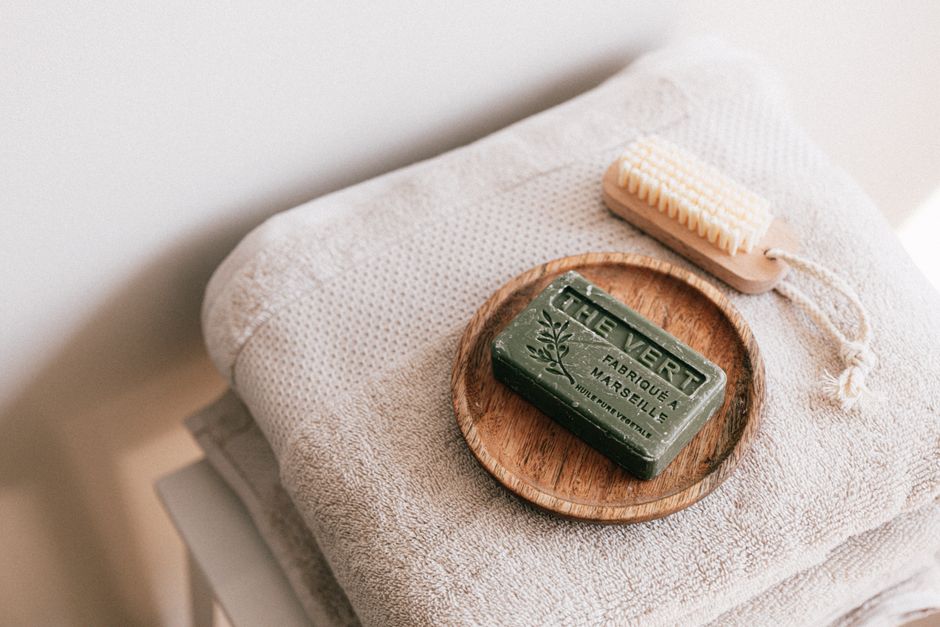 Natural organic soap on wooden holder with eco-friendly brush on clean folded towels