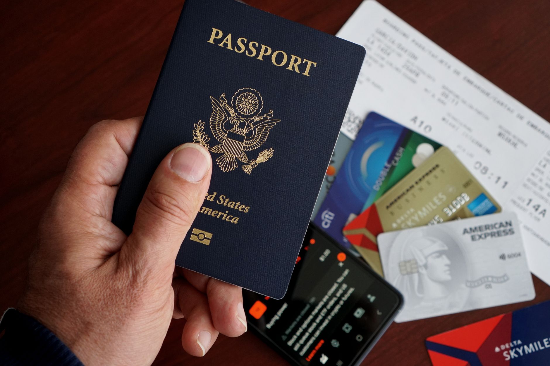Travel documents spread on a table: US passport, printed eVisa confirmation, flight tickets, and a smartphone showing the Nusuk app